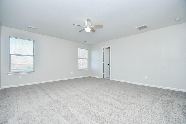 unfurnished room featuring a wealth of natural light, ceiling fan, and carpet