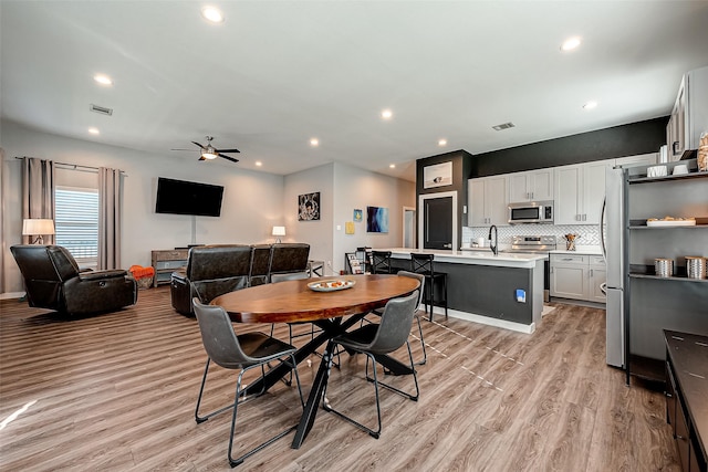 dining area with ceiling fan, light wood-type flooring, and sink