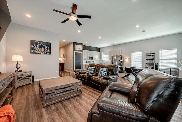 living room with a healthy amount of sunlight, ceiling fan, and light hardwood / wood-style flooring