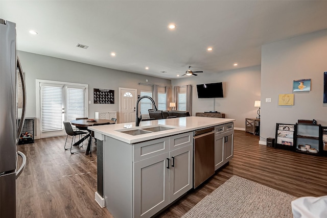 kitchen featuring gray cabinets, appliances with stainless steel finishes, an island with sink, ceiling fan, and sink