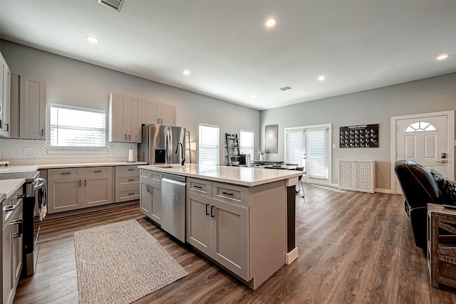 kitchen with hardwood / wood-style flooring, a center island, stainless steel appliances, tasteful backsplash, and gray cabinets