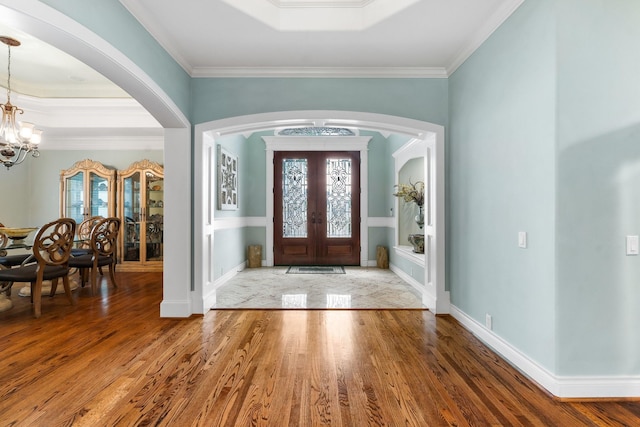 entrance foyer with a notable chandelier, french doors, hardwood / wood-style floors, and crown molding