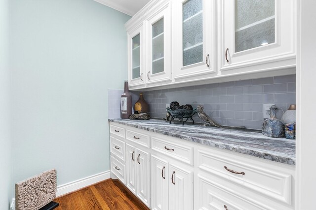 bar featuring white cabinetry, light stone counters, ornamental molding, tasteful backsplash, and dark hardwood / wood-style flooring