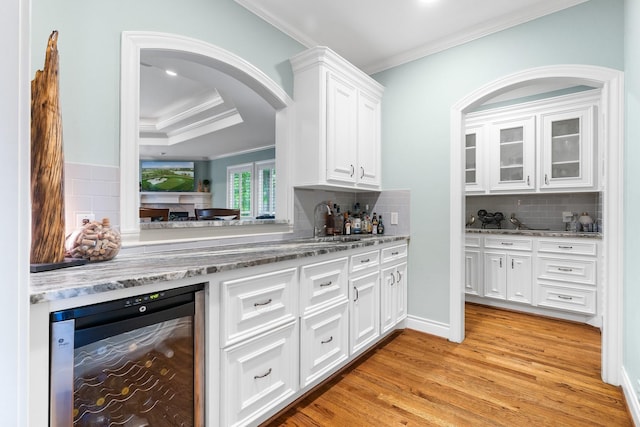 kitchen featuring light hardwood / wood-style flooring, wine cooler, backsplash, and white cabinetry