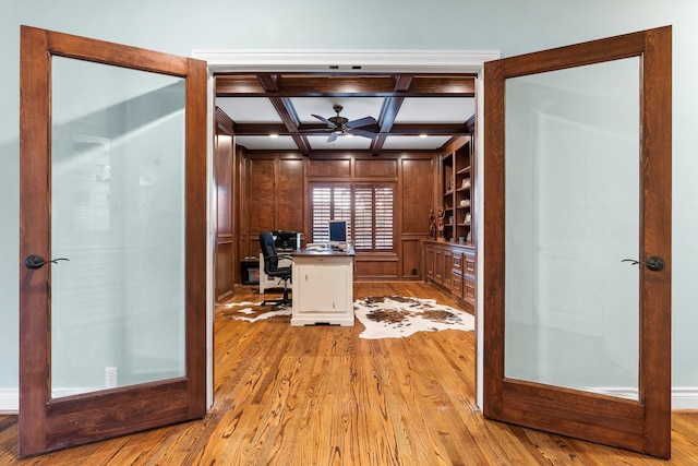 office with coffered ceiling, light wood-type flooring, ceiling fan, french doors, and beam ceiling