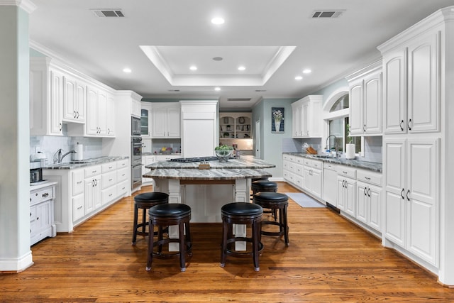 kitchen with a center island, stone countertops, wood-type flooring, and white cabinetry