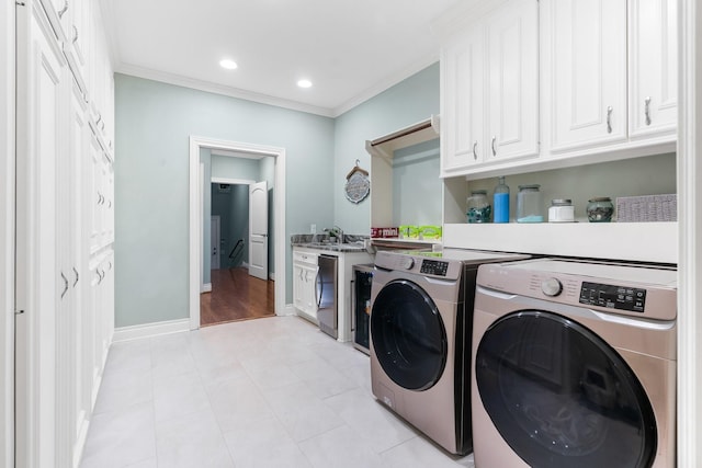 washroom with washer and dryer, cabinets, crown molding, and sink