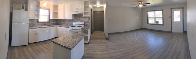 kitchen featuring white appliances, white cabinetry, sink, backsplash, and ceiling fan