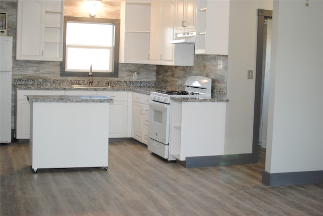 kitchen with white appliances, a kitchen island, white cabinetry, sink, and light stone counters