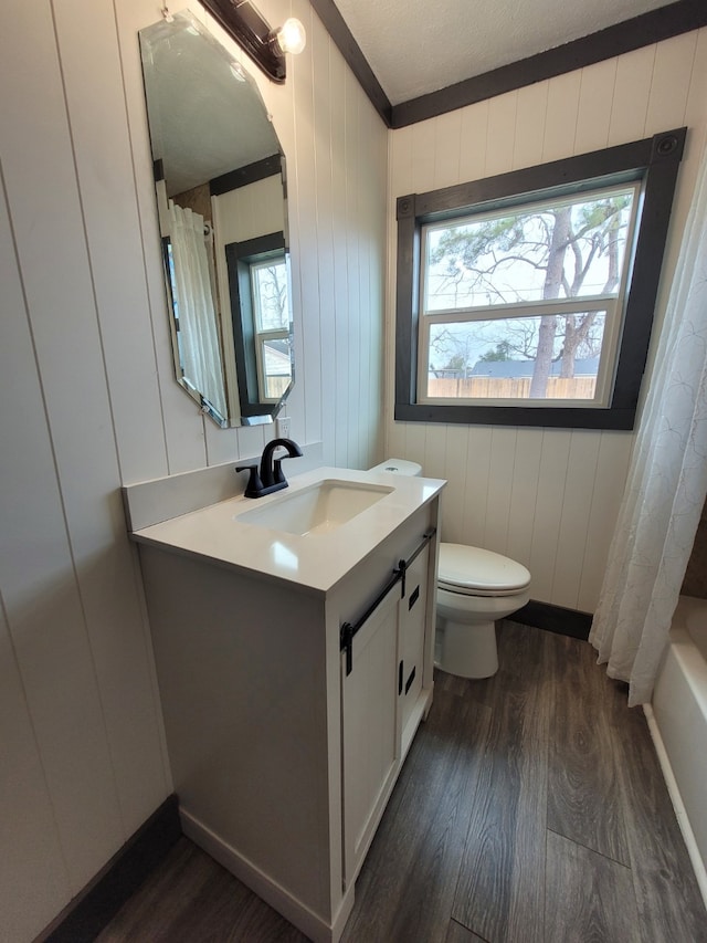 full bathroom featuring hardwood / wood-style floors, toilet, vanity, and wood walls