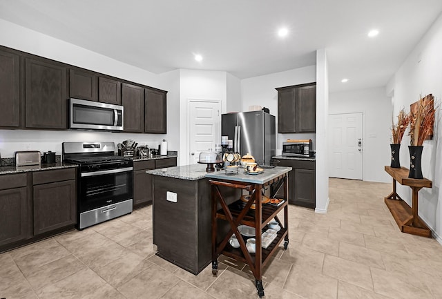 kitchen featuring appliances with stainless steel finishes, a kitchen breakfast bar, light stone countertops, a kitchen island, and dark brown cabinetry