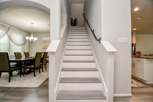 stairs featuring hardwood / wood-style flooring and a notable chandelier