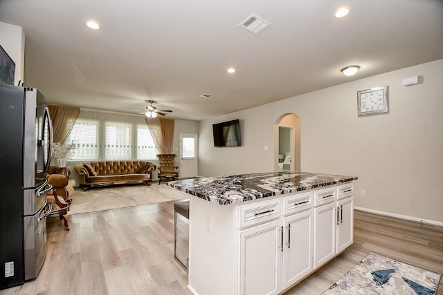 kitchen featuring stainless steel fridge with ice dispenser, white cabinetry, ceiling fan, light wood-type flooring, and a center island