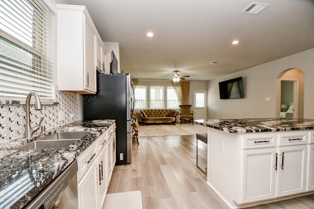 kitchen featuring white cabinets, stainless steel appliances, dark stone counters, tasteful backsplash, and light hardwood / wood-style flooring