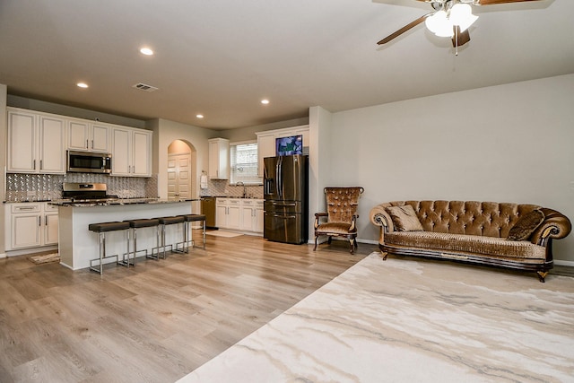 living room with ceiling fan, light hardwood / wood-style floors, and sink