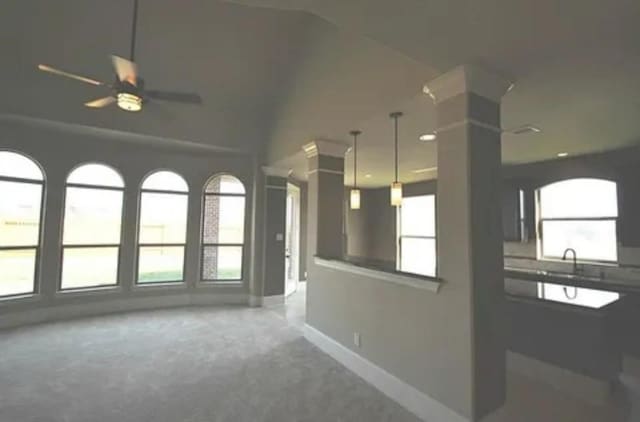 carpeted spare room featuring ceiling fan, sink, and decorative columns