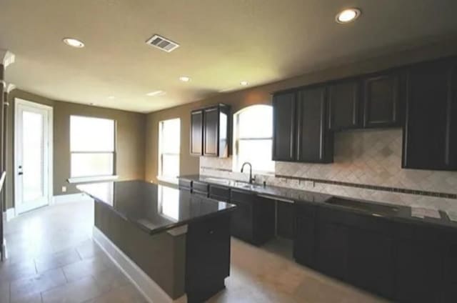 kitchen featuring cooktop, decorative backsplash, and a center island