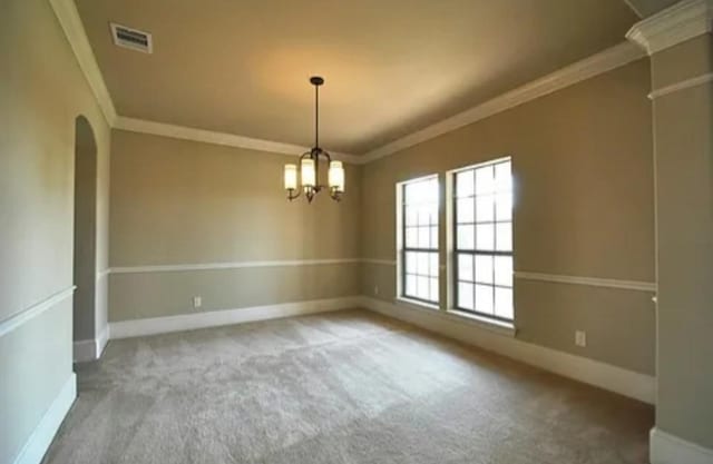 spare room featuring crown molding, a notable chandelier, and carpet flooring