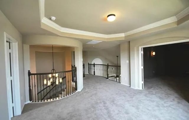 interior space featuring a notable chandelier, crown molding, a raised ceiling, and carpet floors