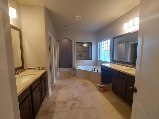 bathroom featuring tiled tub and vanity