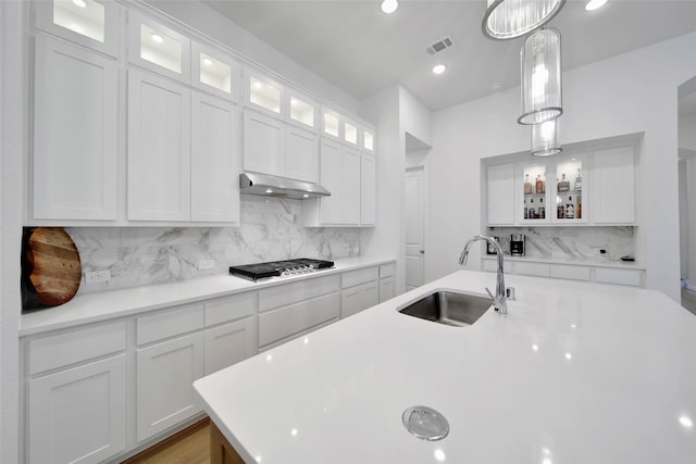 kitchen with decorative light fixtures, sink, white cabinets, and tasteful backsplash