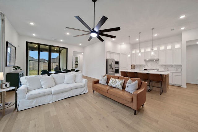 living room featuring ceiling fan, light hardwood / wood-style floors, and sink