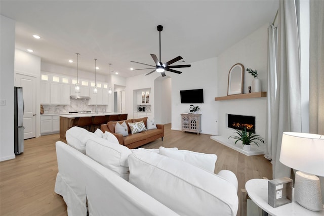 living room with ceiling fan, a fireplace, and light hardwood / wood-style flooring