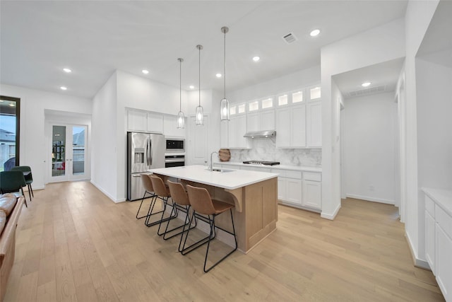 kitchen with stainless steel appliances, decorative backsplash, white cabinets, and sink