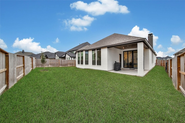 rear view of property featuring a lawn and a patio area