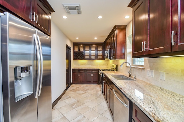 kitchen with tasteful backsplash, sink, stainless steel appliances, light tile patterned floors, and light stone counters