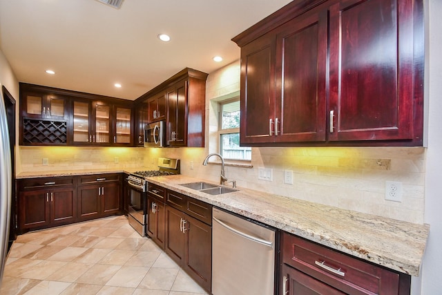 kitchen with stainless steel appliances, backsplash, light tile patterned flooring, light stone countertops, and sink