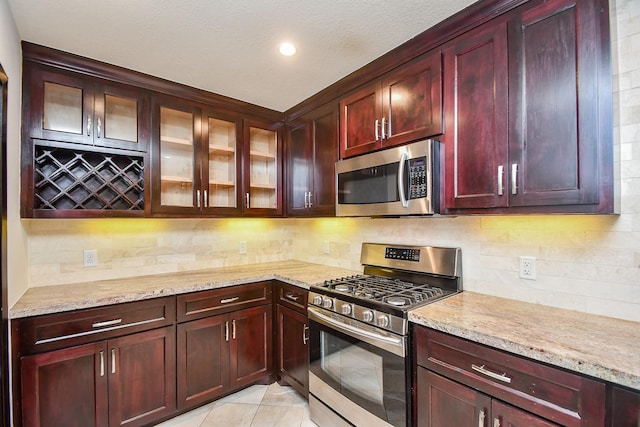 kitchen featuring light stone counters, tasteful backsplash, stainless steel appliances, and light tile patterned flooring