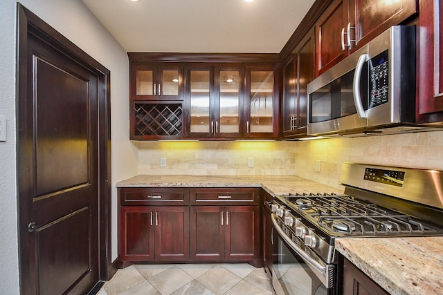 kitchen featuring tasteful backsplash, light tile patterned flooring, light stone counters, and stainless steel appliances