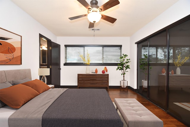 bedroom with ceiling fan, dark wood-type flooring, and multiple windows