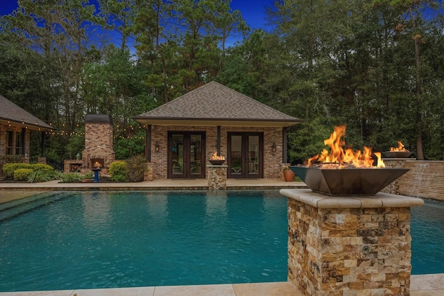 view of pool with an outdoor fireplace, a patio, a fire pit, and an outdoor structure