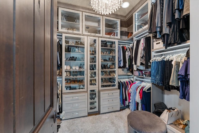 walk in closet with light carpet and an inviting chandelier