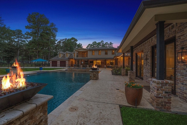 pool at dusk with a patio area and a fire pit