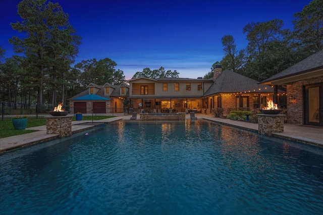 pool at dusk with an outdoor fire pit and a patio