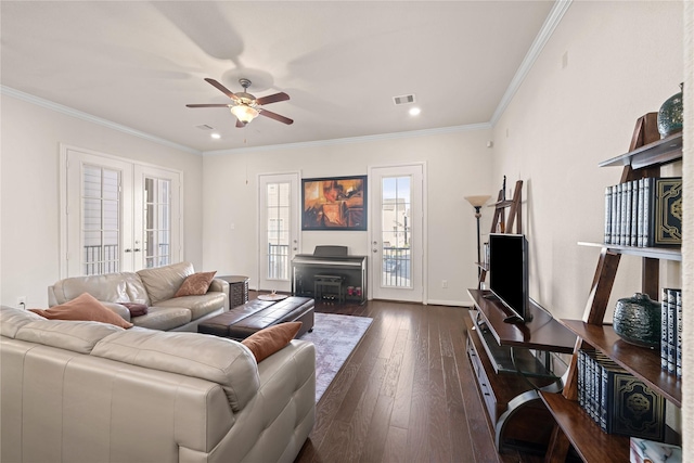 living room with a fireplace, ceiling fan, crown molding, dark wood-type flooring, and french doors