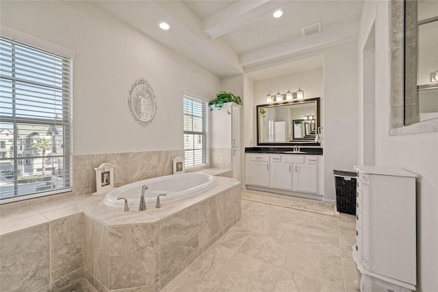 bathroom with beamed ceiling, vanity, and tiled tub