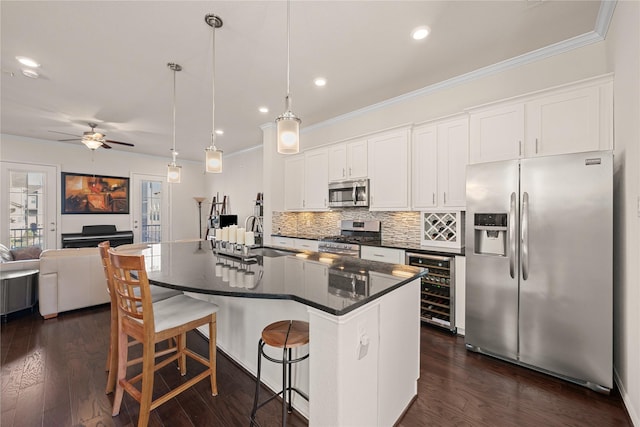 kitchen featuring pendant lighting, a breakfast bar, a kitchen island with sink, stainless steel appliances, and white cabinets