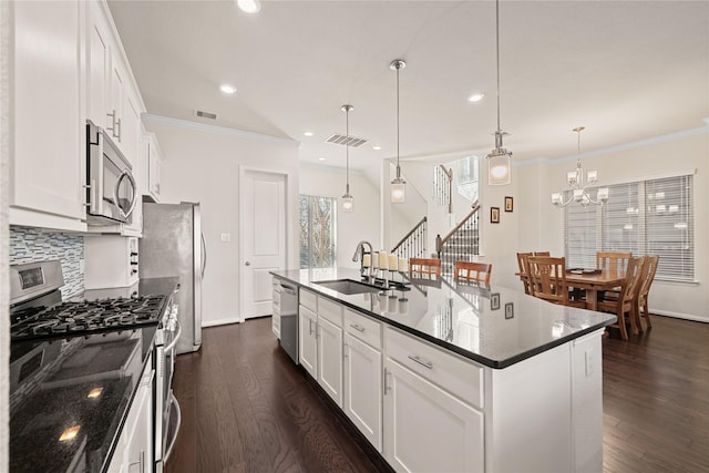 kitchen with pendant lighting, sink, appliances with stainless steel finishes, a kitchen island with sink, and white cabinetry