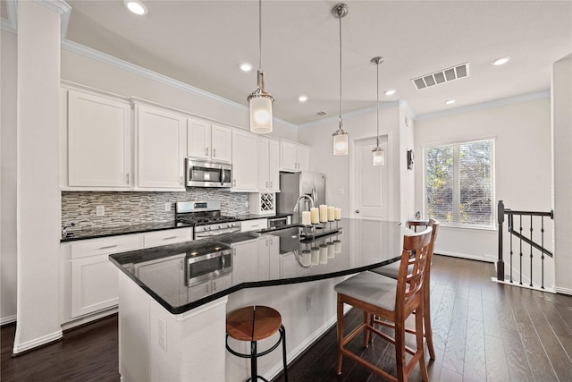 kitchen featuring white cabinetry, a kitchen breakfast bar, an island with sink, and appliances with stainless steel finishes