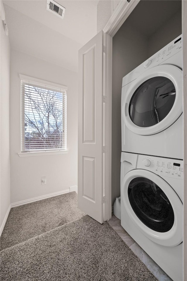 laundry room featuring stacked washer / drying machine and carpet floors