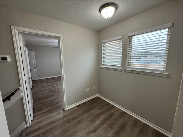 empty room with a textured ceiling and dark hardwood / wood-style floors