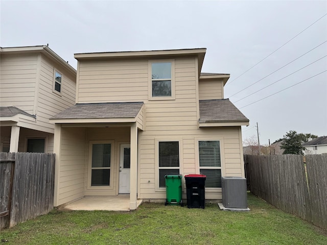 back of house with central AC unit, a patio area, and a yard