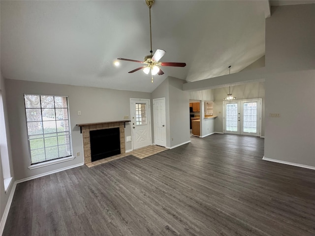 unfurnished living room featuring ceiling fan, a healthy amount of sunlight, dark hardwood / wood-style floors, and a tile fireplace