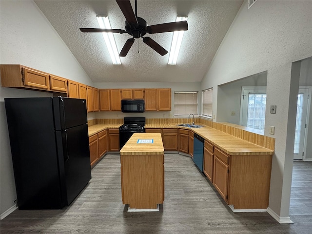 kitchen featuring black appliances, sink, a textured ceiling, and a center island