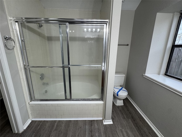 bathroom with bath / shower combo with glass door, wood-type flooring, and toilet