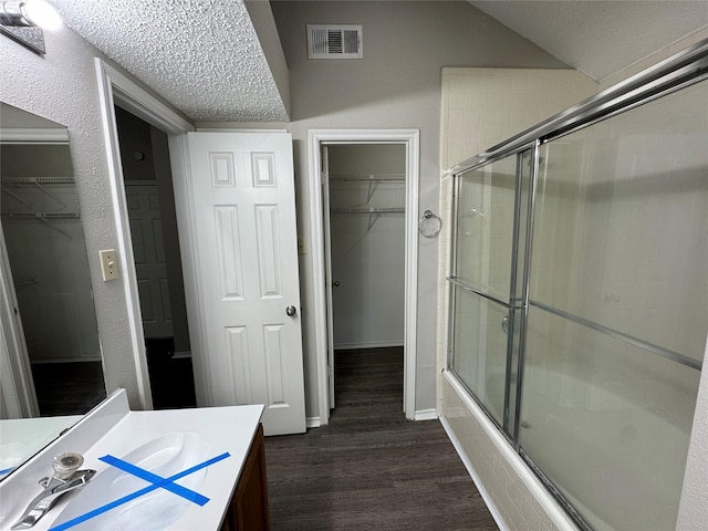 bathroom featuring vanity, shower / bath combination with glass door, a textured ceiling, and hardwood / wood-style flooring